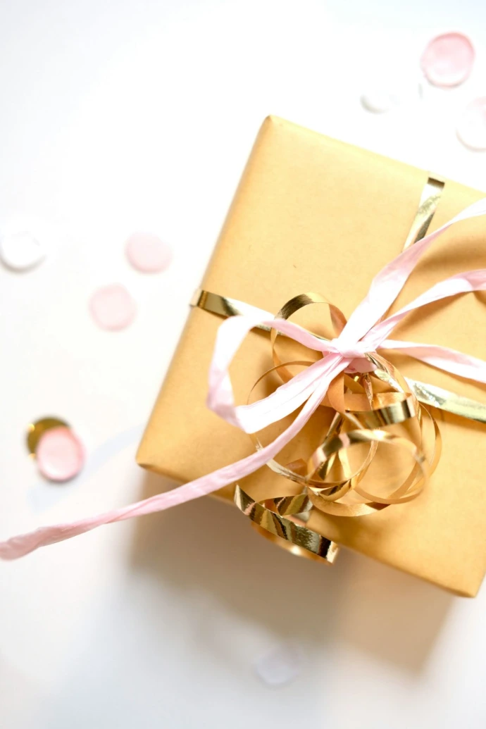 A golden gift box tied with pink and gold ribbons
